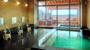 Un espace piscine avec vue sur la plage, un coin salon couvert et un mur carrelé avec un plafond en bois.