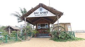 A beachside cafe named 'Bay Spirit' with a thatched roof and large wheels in front. - Lotus an Eco Resort Konark (Gop)
