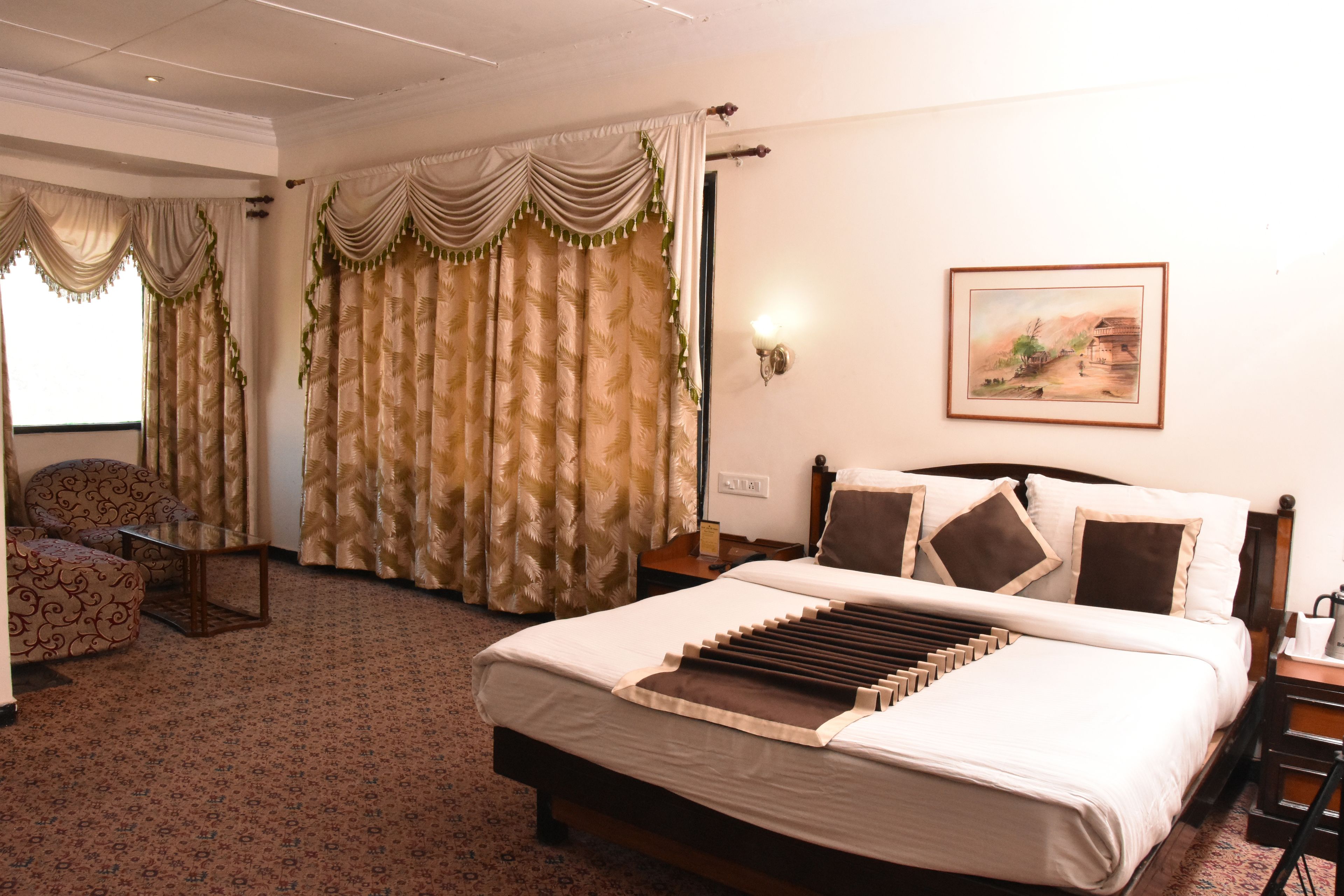Una habitación de hotel con una cama grande, una silla, un escritorio y cortinas.