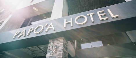 The exterior of Papa'a Hotel with a prominent sign and a brick pillar.