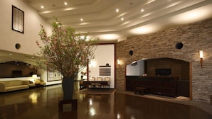 A spacious lobby with a stone fireplace, a seating area with a table and chairs, and a potted plant. - Odakyu Hotel de Yama (Hakone)