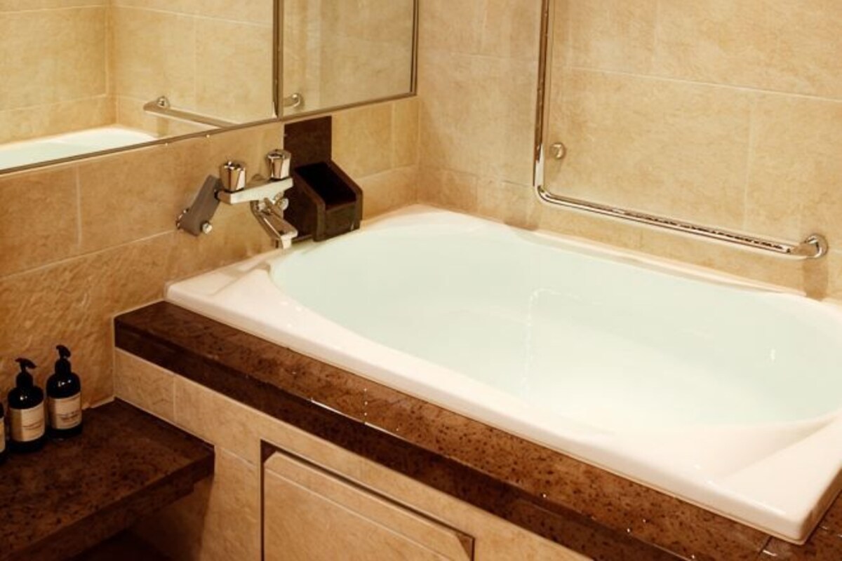 Un baño con bañera, espejo y barra para toallas.