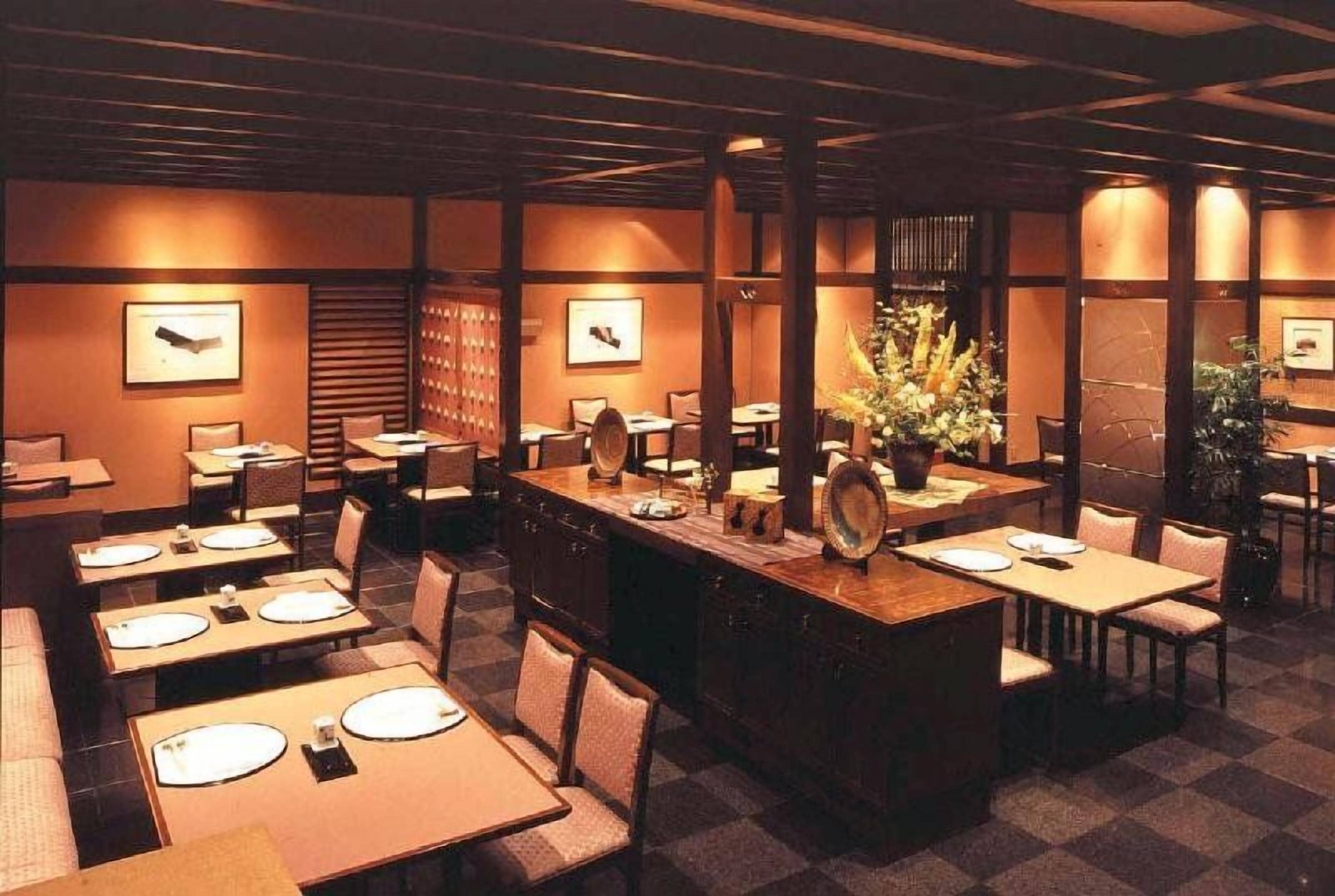 A restaurant with a checkered floor, wooden tables, and chairs, and framed pictures on the walls.