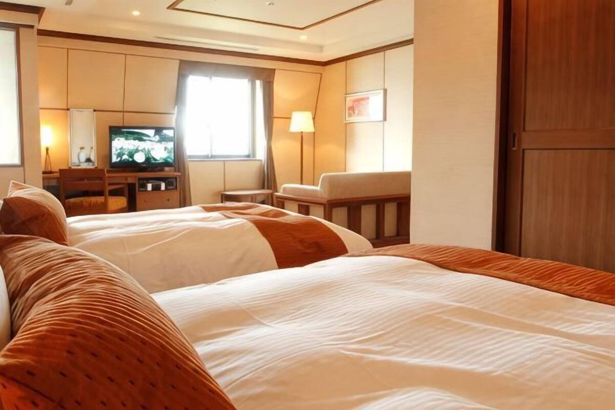 Habitación de hotel con dos camas, televisión, escritorio y silla.
