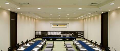 A conference room with a long table, chairs, and a blue carpet.