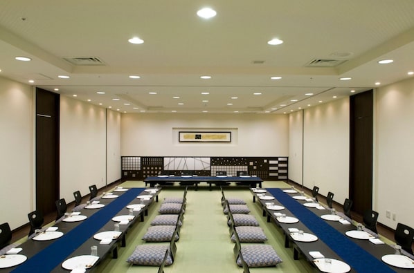 Una sala de conferencias con una larga mesa, sillas y una alfombra azul.