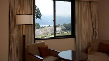 A room with two chairs, a table, and a large window with curtains.