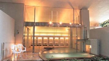 An indoor space with a central seating area, a glass partition, and a water feature.