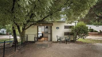 Une maison dotée d’un porche abrité, d’un petit patio avec des chaises et d’une porte visible donnant accès à un espace intérieur.