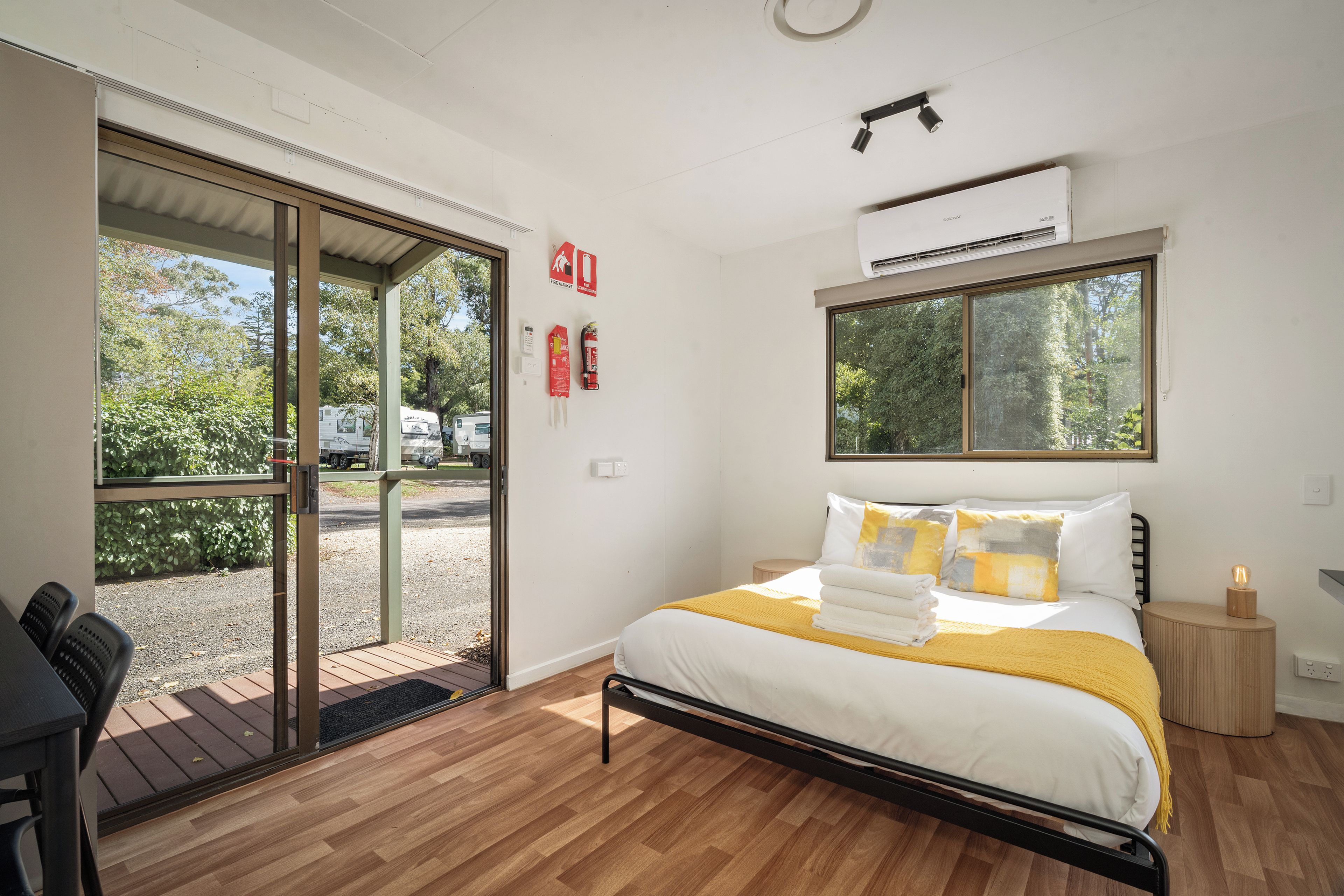Una habitación de hotel con cama, mesita de noche y ventana.