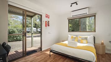Una habitación de hotel con cama, mesita de noche y ventana.