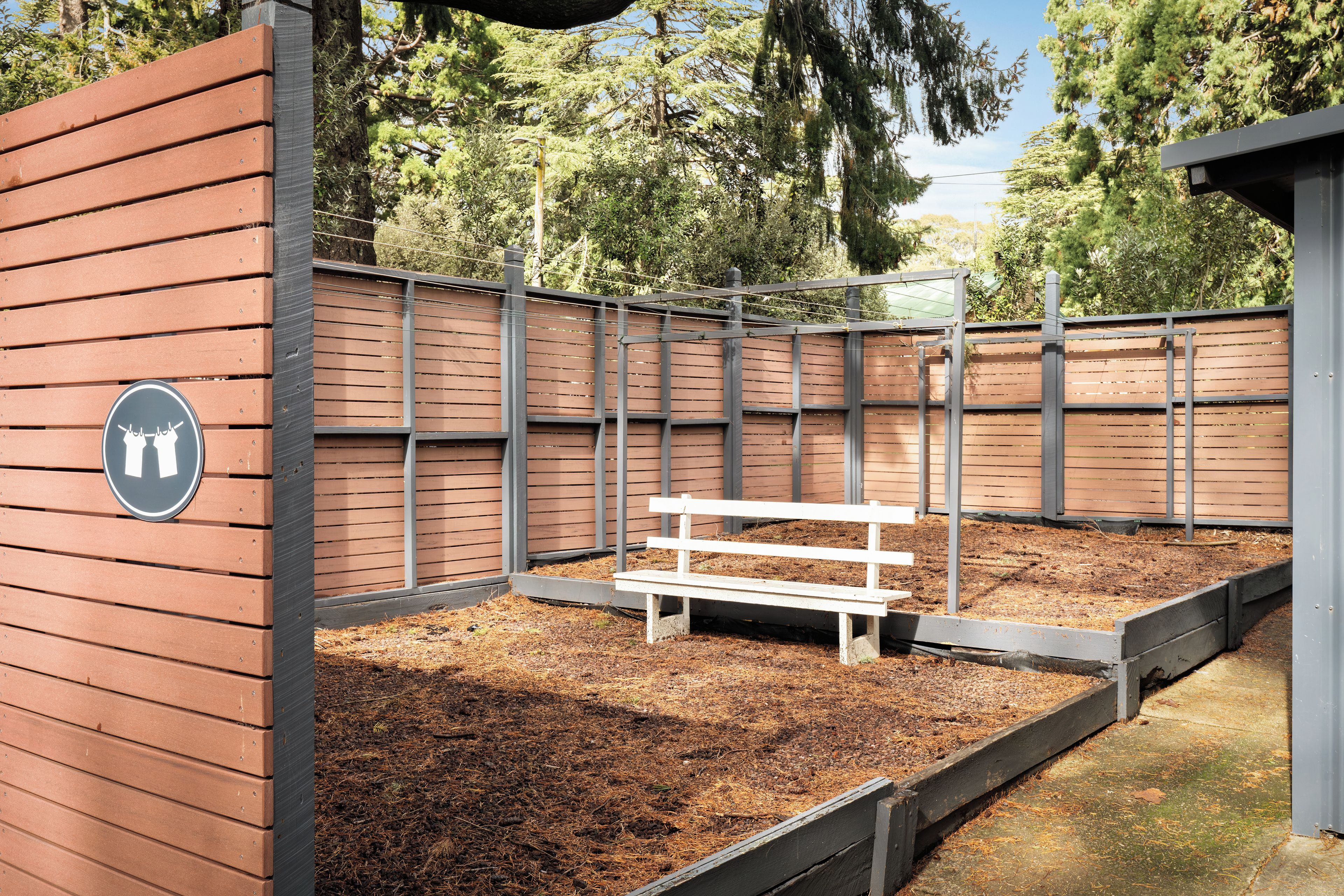 A fenced outdoor area with a bench and a sign indicating a restroom.