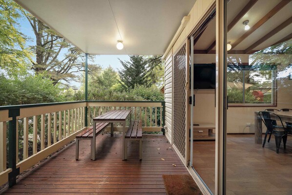 A covered outdoor area with a wooden deck, a table, and chairs.