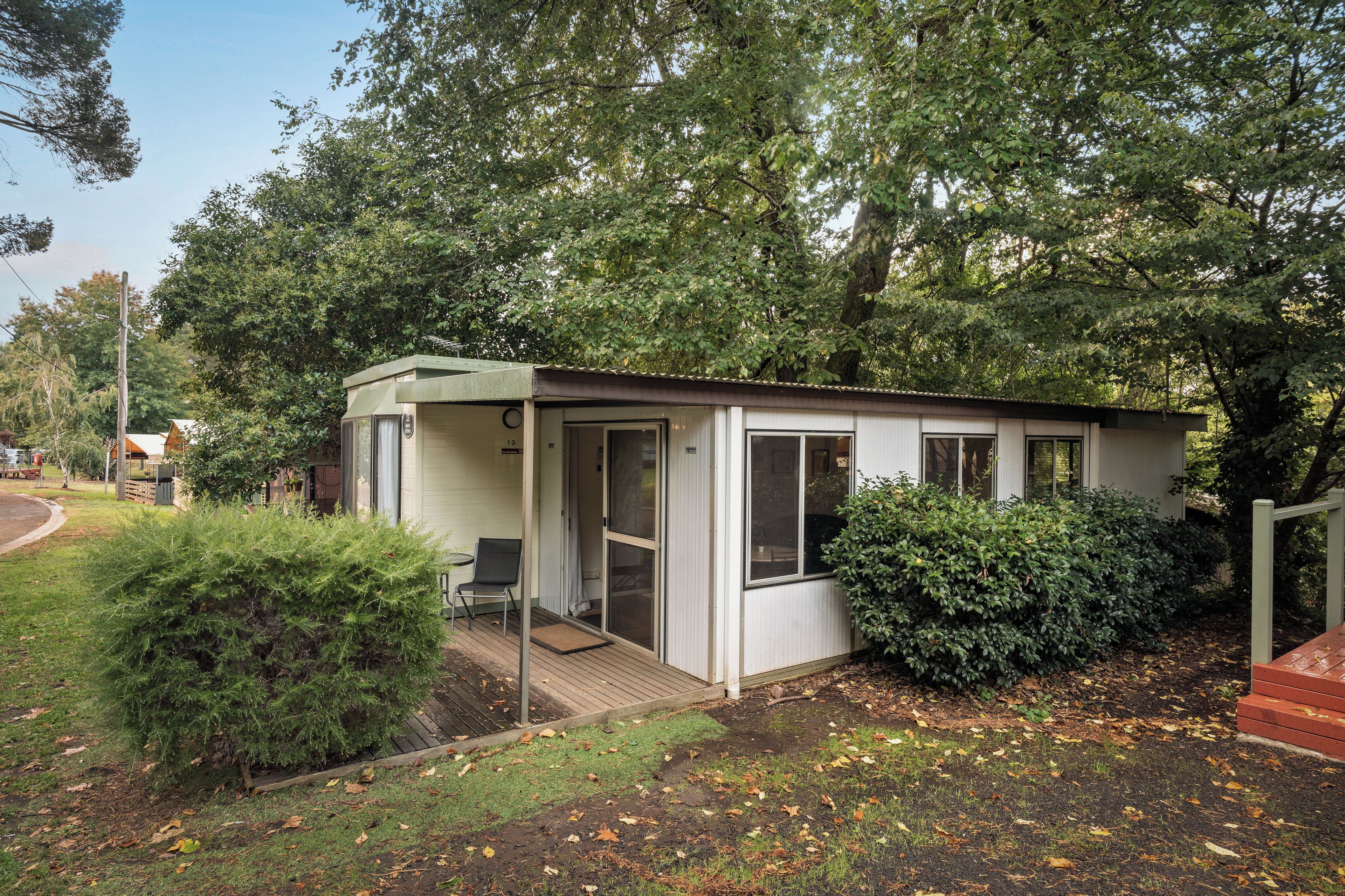 A small, single-story cabin with a covered porch, a screened door, and a window.