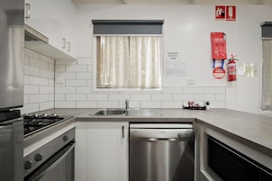 Una cocina moderna con baldosas blancas, electrodomésticos de acero inoxidable, un ventanal con cortinas y equipo de seguridad contra incendios.