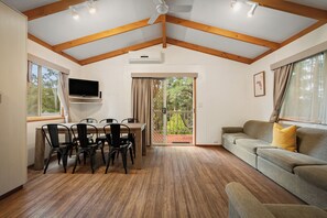 Una habitación amplia con zona de comedor, sofá y televisor.