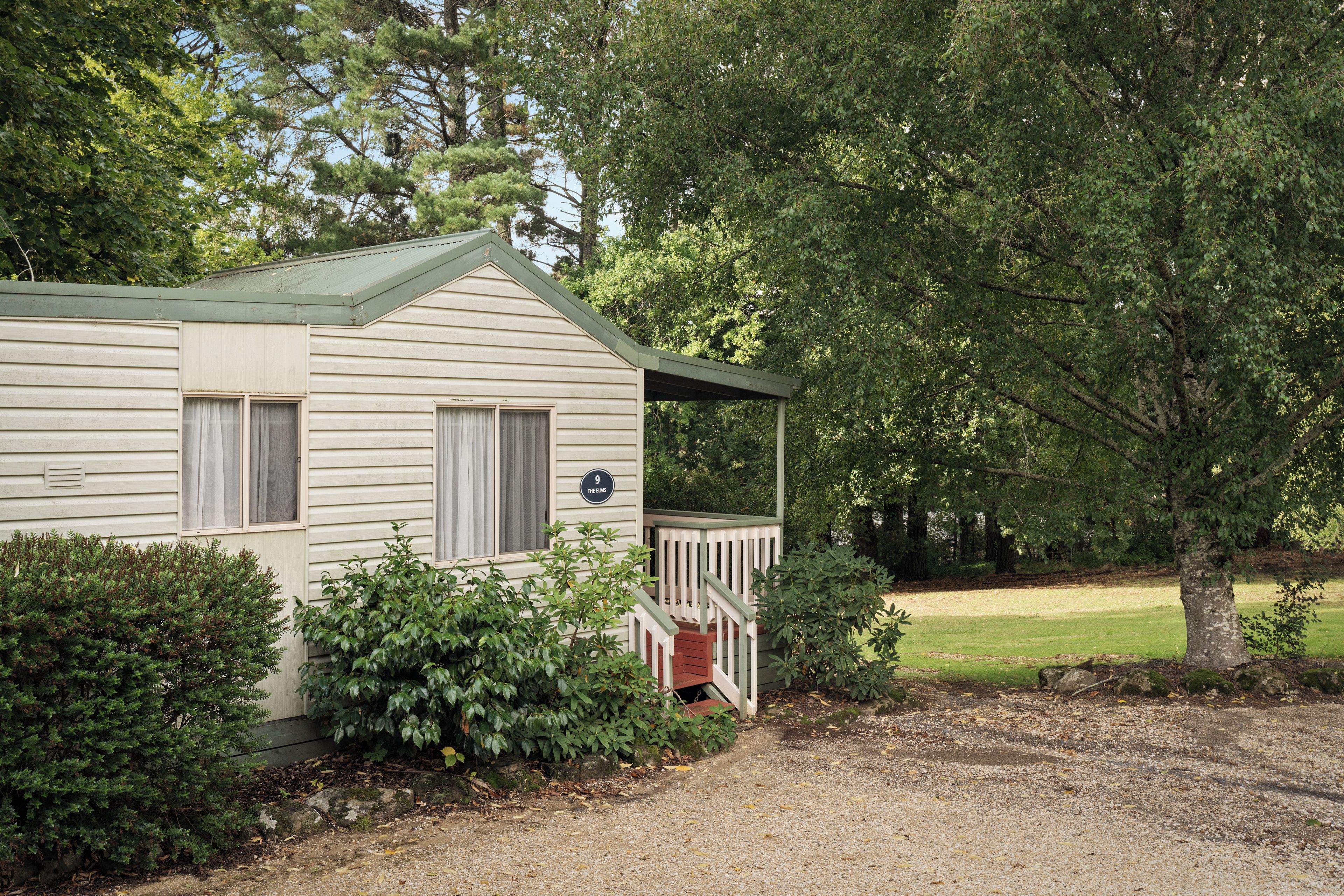 A single-story house with a porch, a mailbox, and a number sign indicating '9 THE ELMS'.