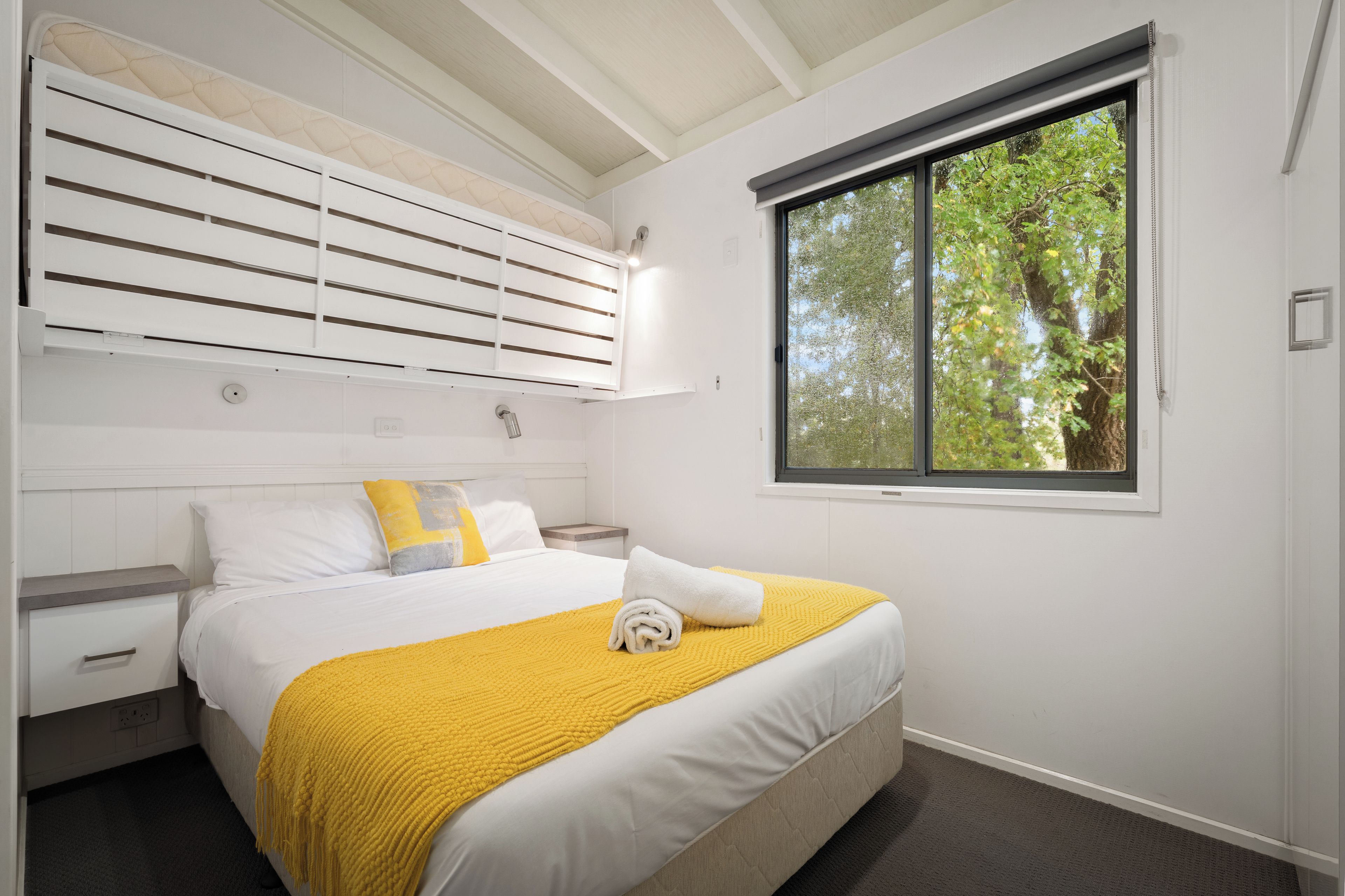 A bedroom with a bed, a window, and a built-in headboard.