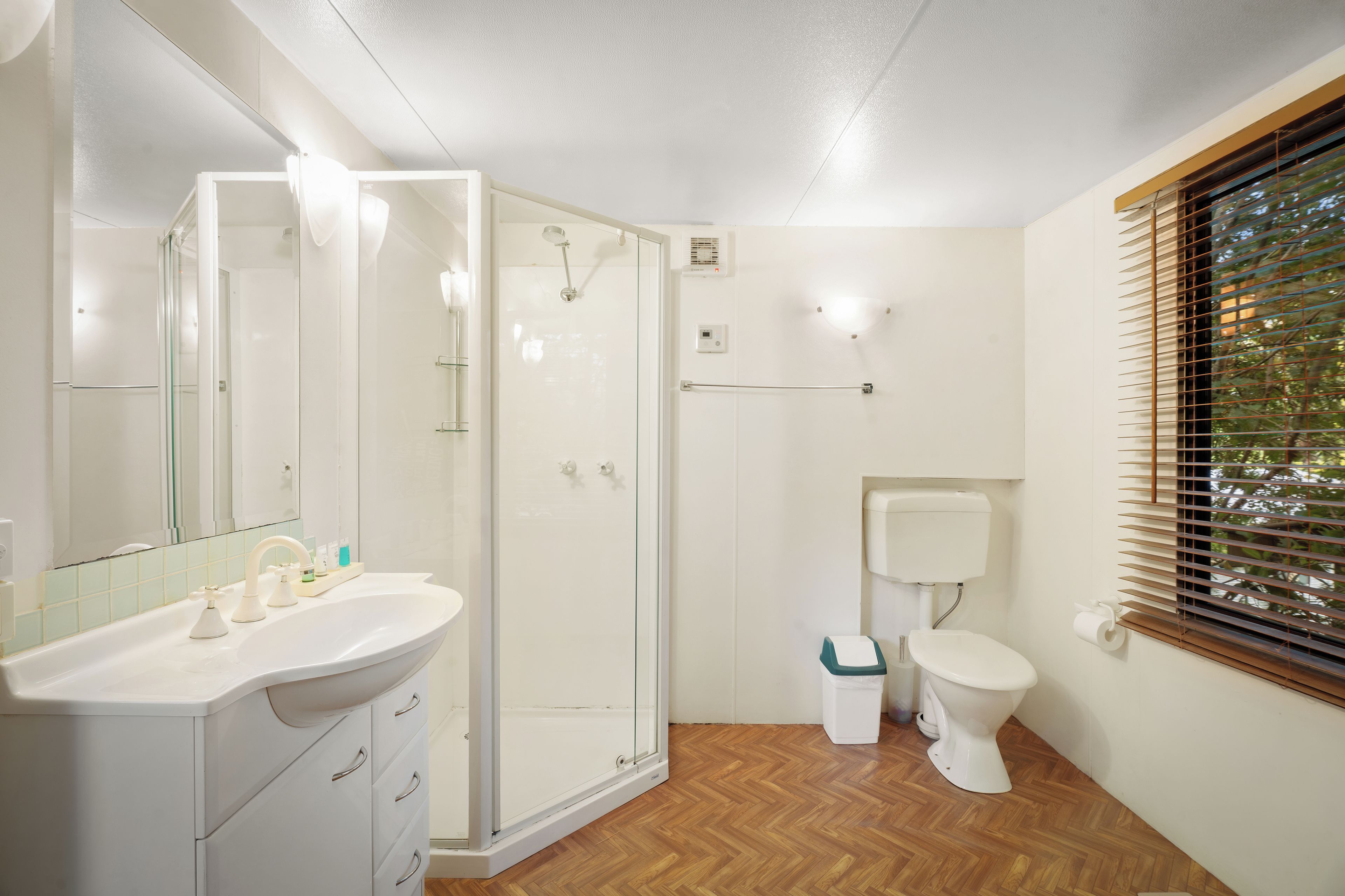 Une salle de bain moderne avec une douche à parois de verre, un lavabo blanc avec un miroir et des toilettes.