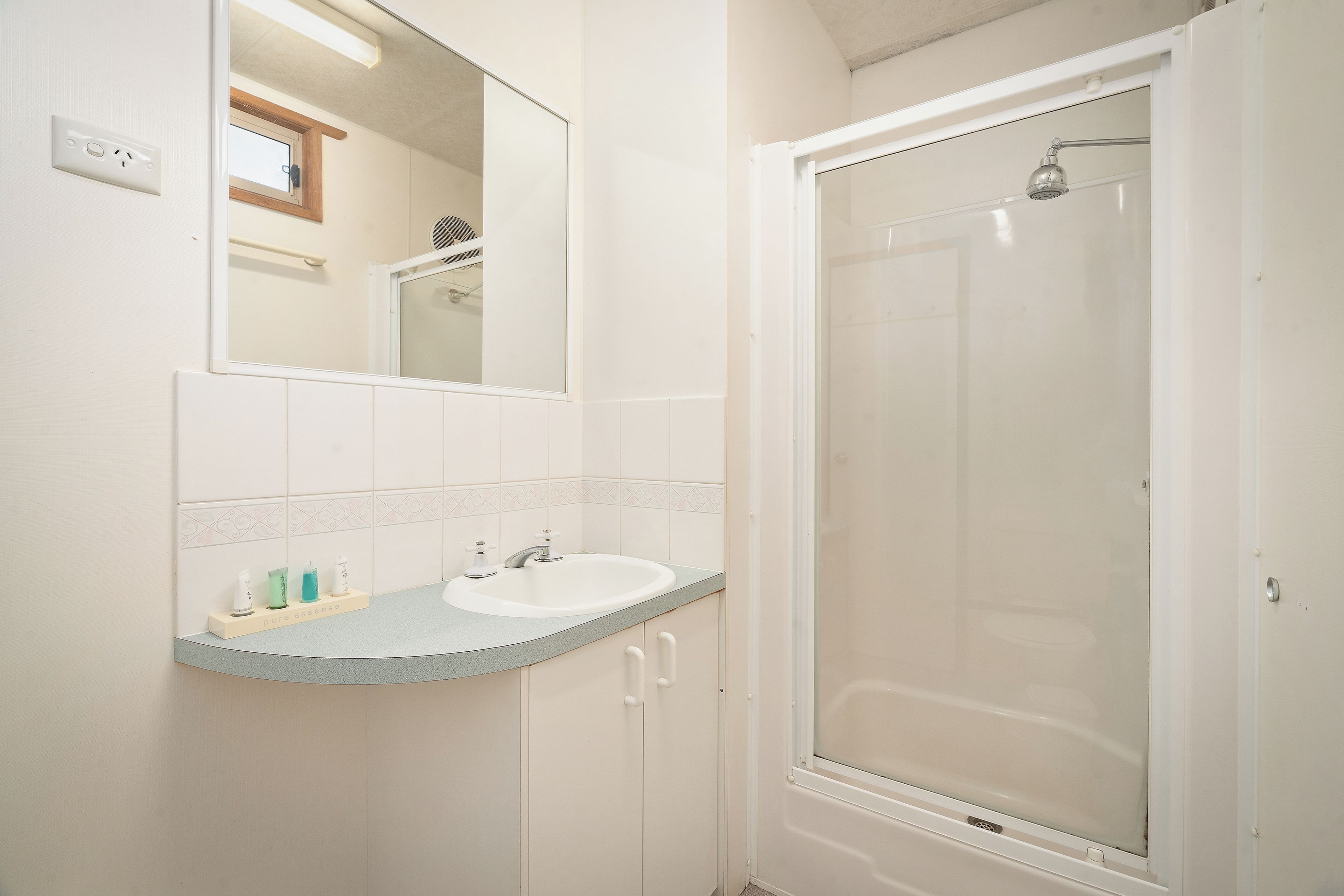 A bathroom with a shower, a sink, and a mirror.