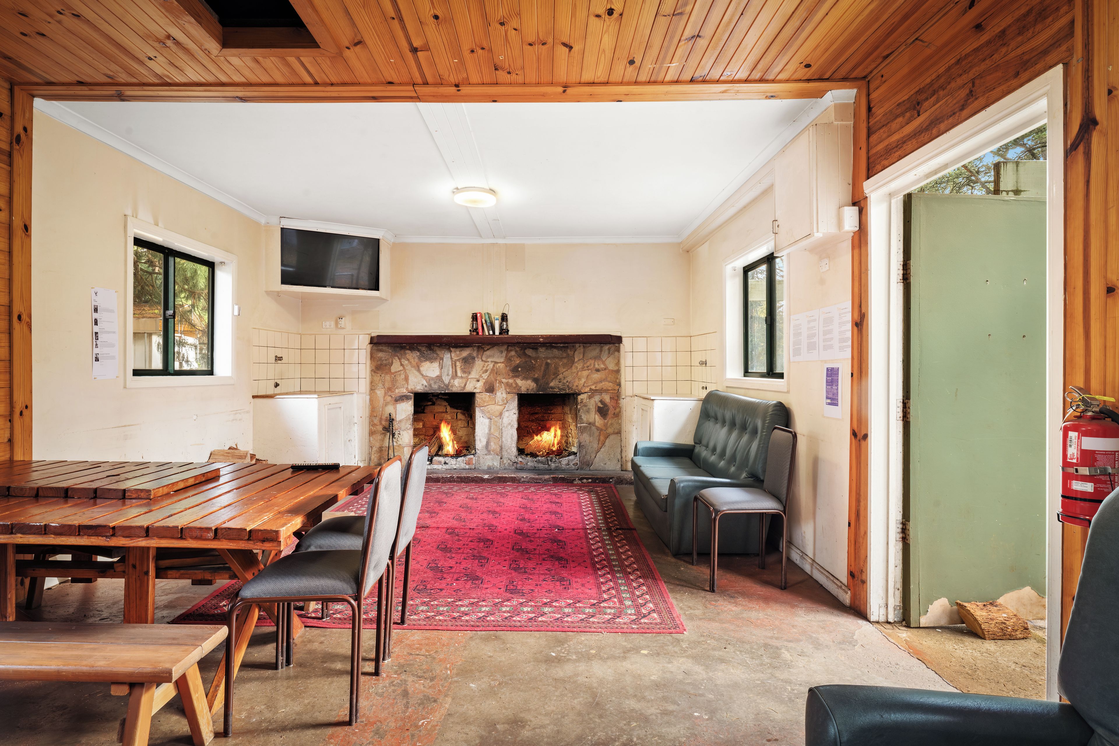 A cozy room with a stone fireplace, seating, and a television.