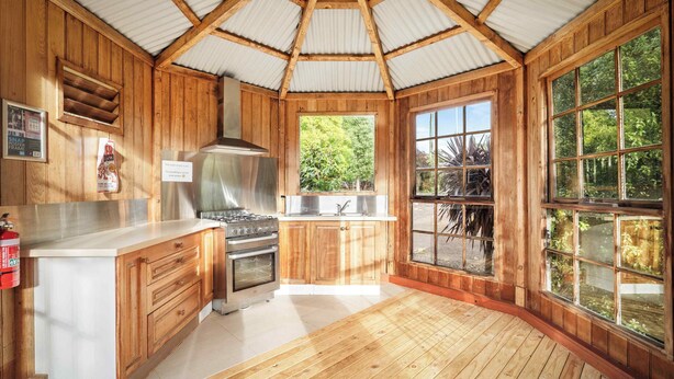 Un intérieur en bois avec une cuisine, de grandes fenêtres et une vue sur la verdure.