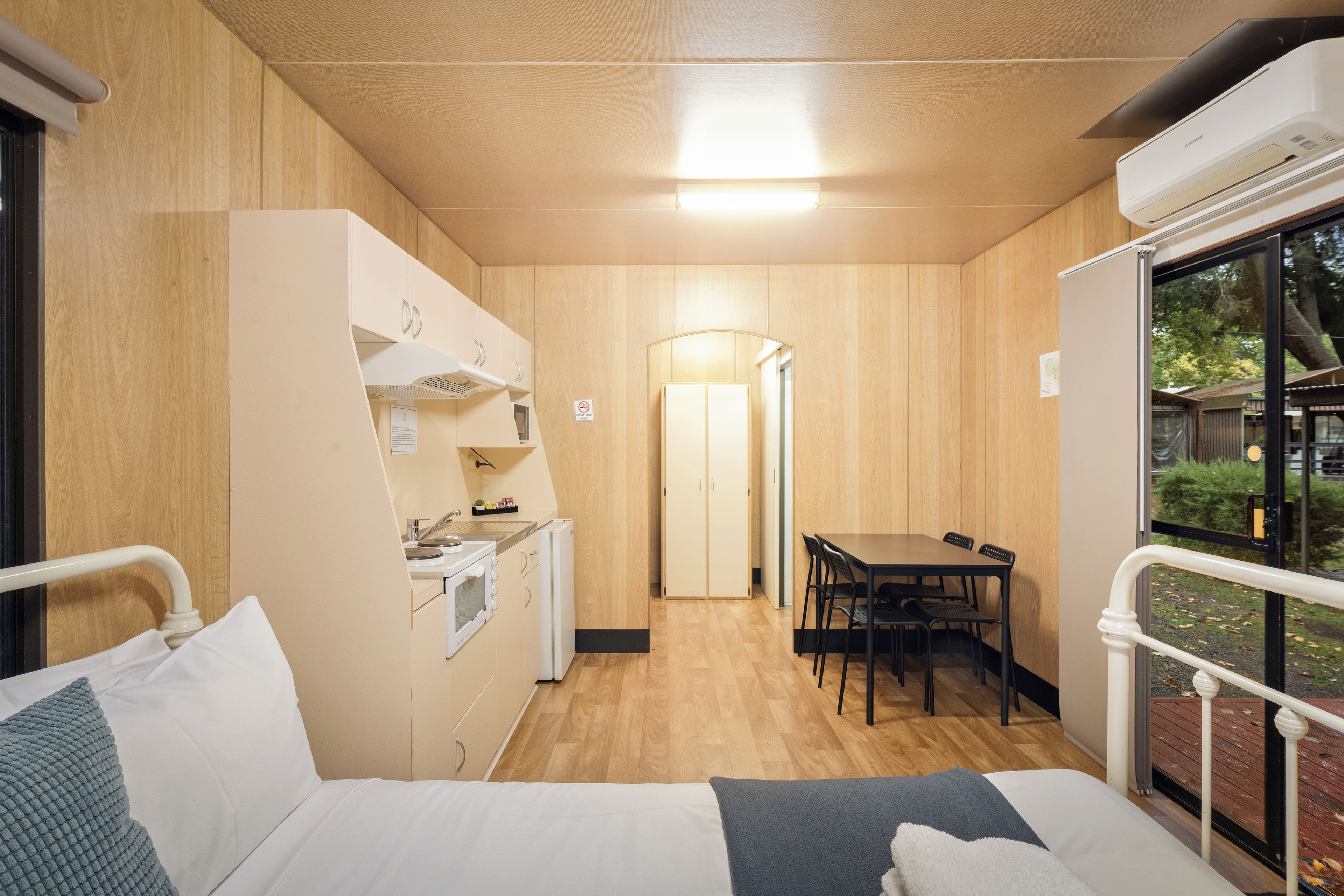 Une pièce de taille modeste comprenant un lit, un coin cuisine, un espace repas et une fenêtre.