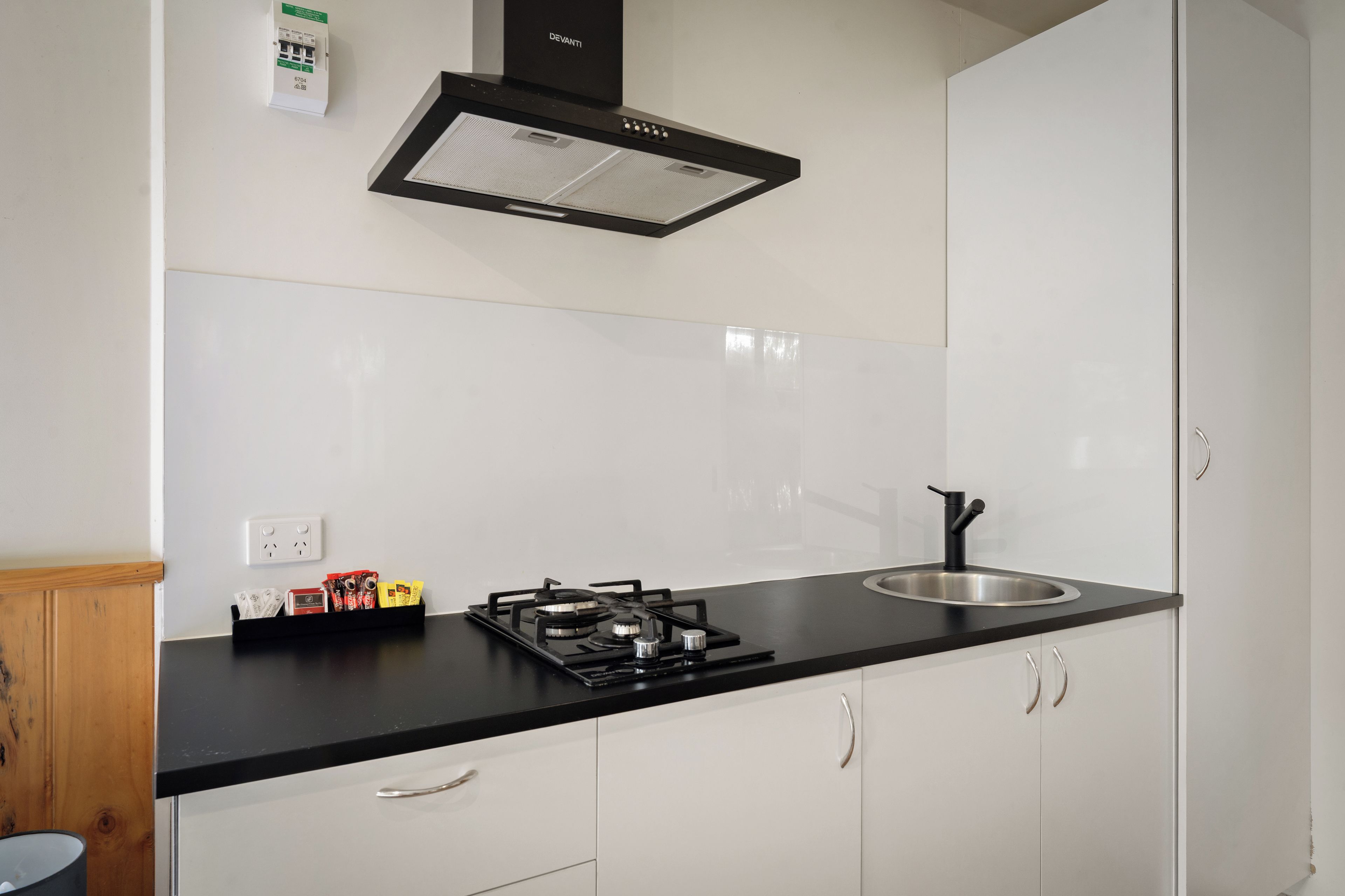 A modern kitchen with a black countertop, stainless steel sink, and a gas stove.