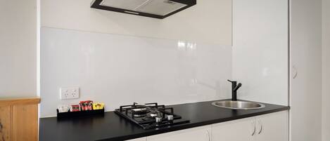A modern kitchen with a black countertop, stainless steel sink, and a gas stove.