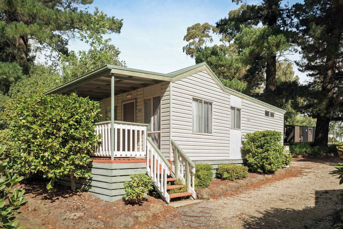 A single-story house with a porch, a staircase, and a small front yard.