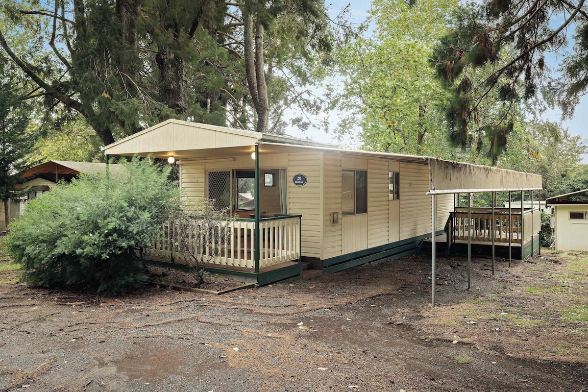 A single-story mobile home with a porch, a small deck, and a covered area.