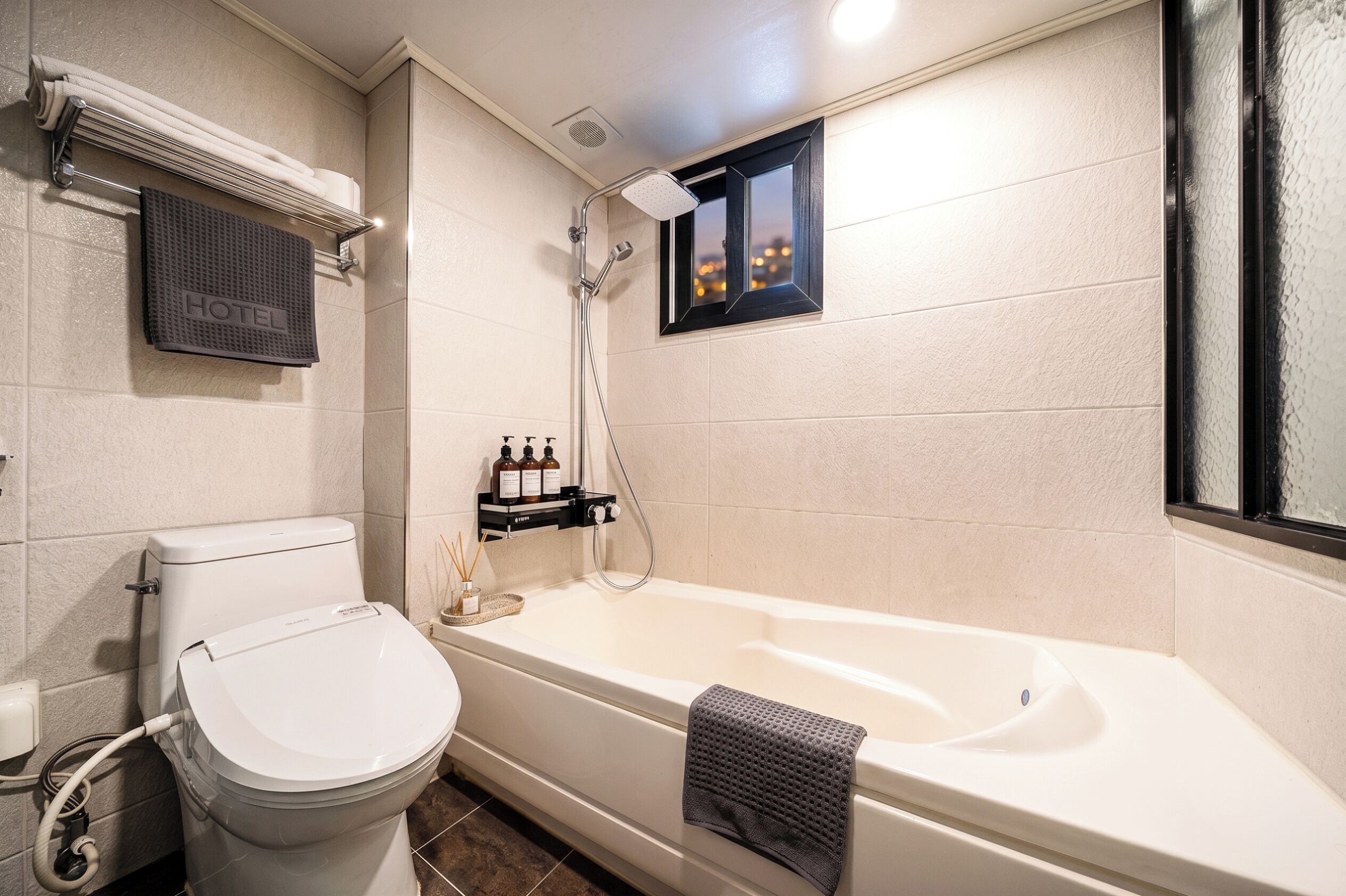 Ein Badezimmer mit Toilette, einer Badewanne, einer Dusche, einem Handtuchhalter und einem kleinen Fenster.
