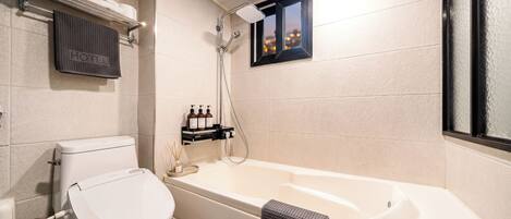 A bathroom with a toilet, a bathtub, a shower, a towel rack, and a small window.