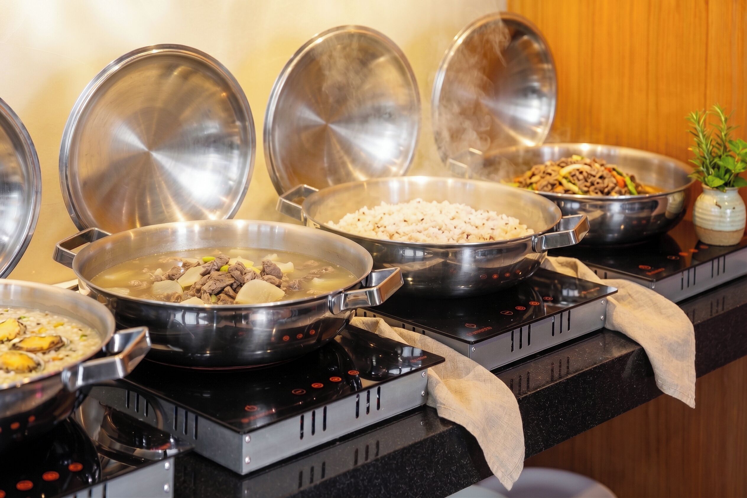 Una encimera de cocina con varias ollas y sartenes sobre una cocina de inducción.