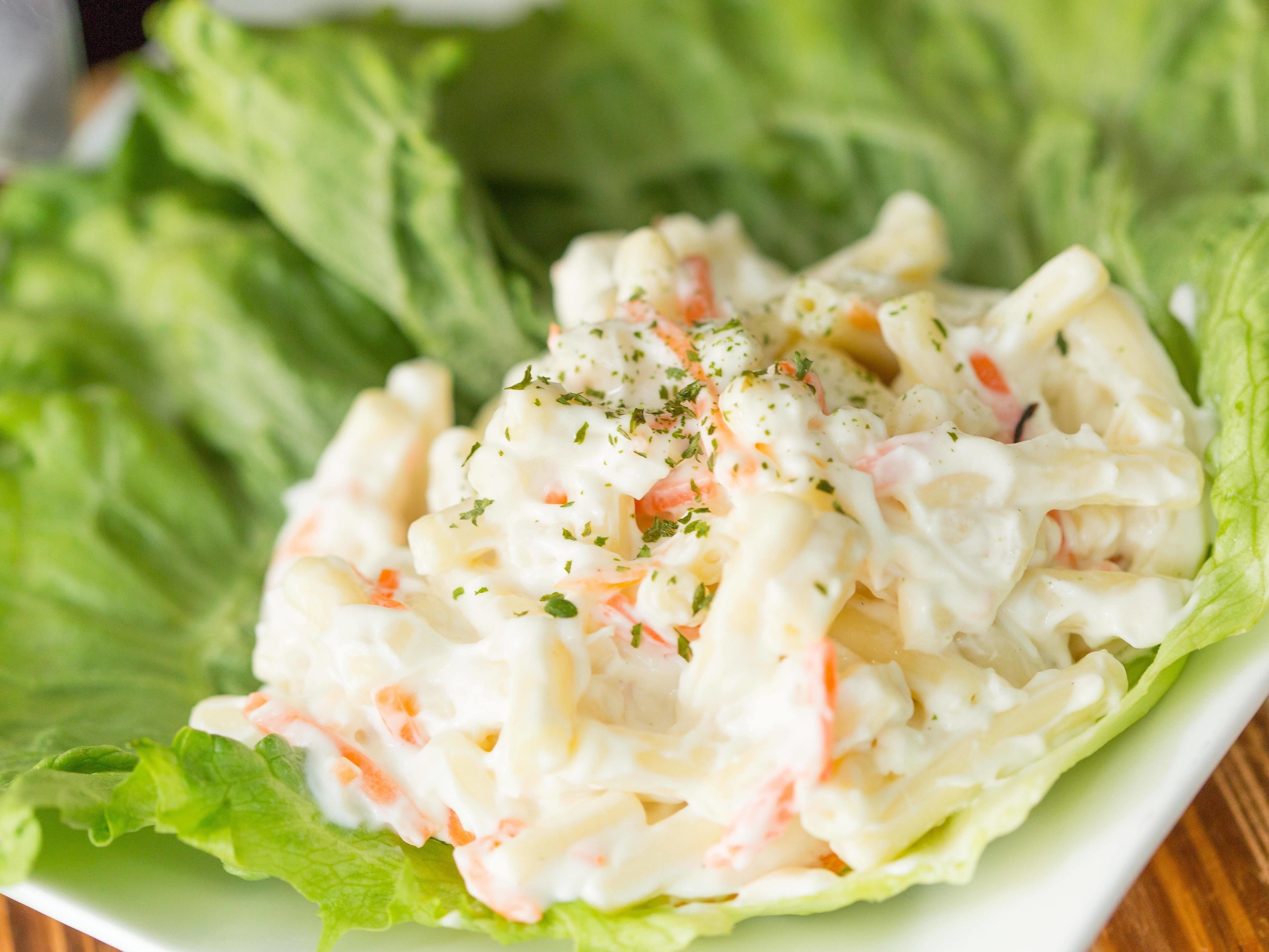 A salad with a creamy dressing, garnished with herbs, served on a bed of lettuce leaves.