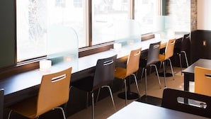 A modern cafe with large windows, wooden tables, and black and yellow chairs. - Hotel AreaOne NOBEOKA (Nobeoka)
