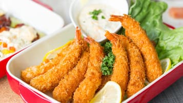 A dish of breaded and fried shrimp served with lemon wedges and a side of dipping sauce.