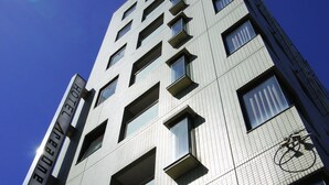 A modern hotel building with a grid-patterned facade, multiple balconies, and a bicycle mounted on the side. - Hotel AreaOne NOBEOKA (Nobeoka)