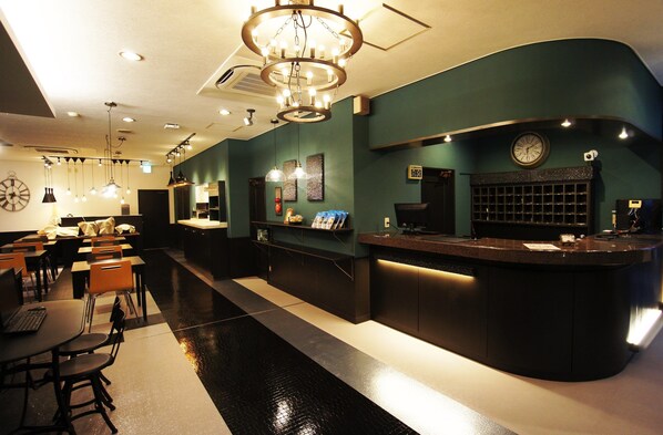 A hotel lobby with a reception desk, seating area, and a clock on the wall.