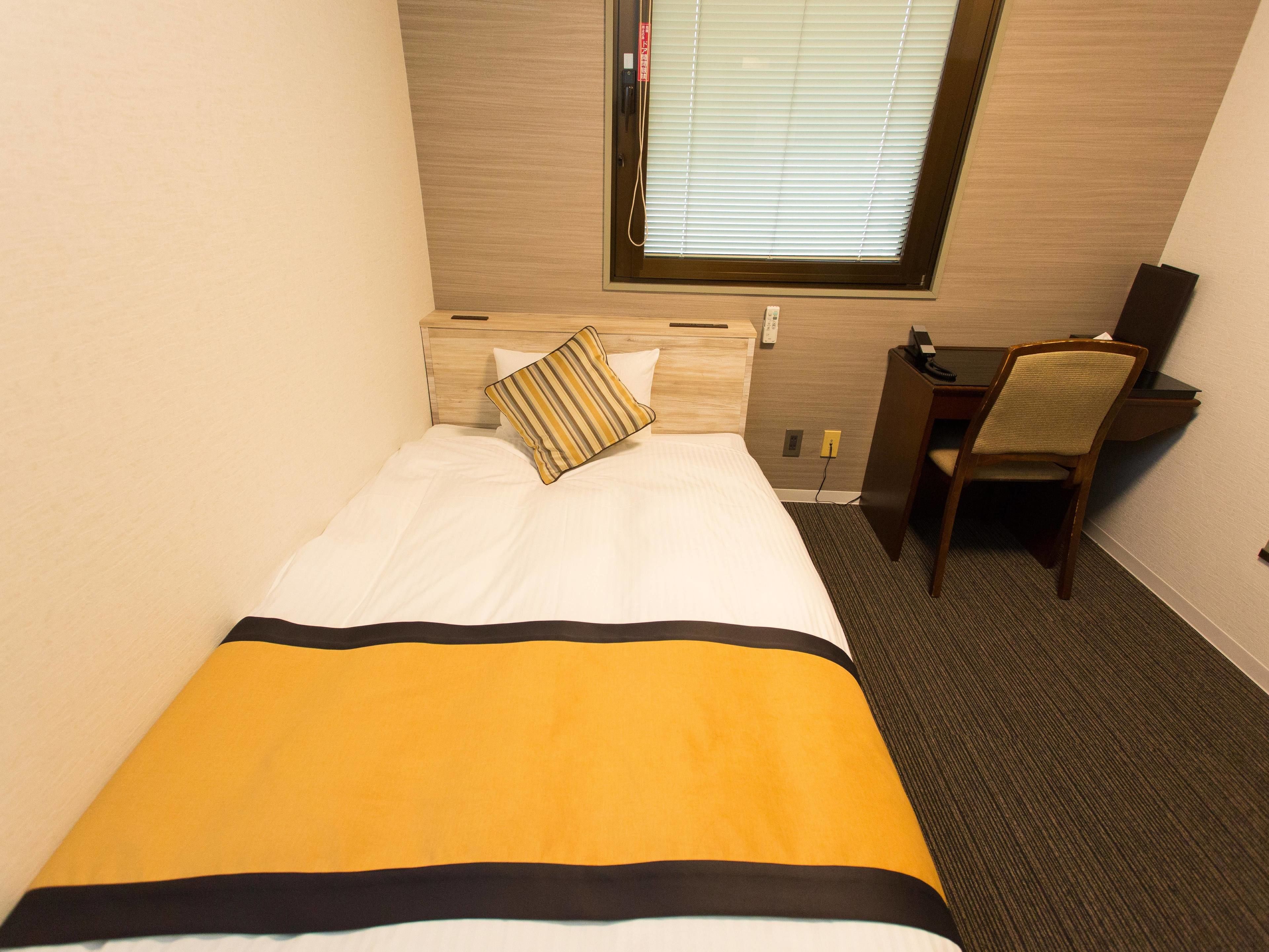Una habitació d'hotel amb un llit, un escriptori i una cadira.