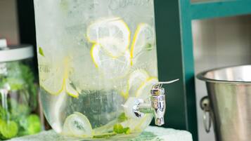 A large glass container with a tap, filled with water and lemon slices, placed on a surface.