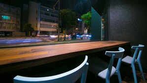 Ein Restaurant mit einem langen Holztisch und zwei weißen Stühlen.