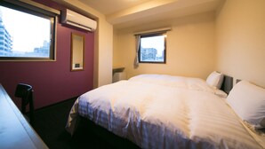 Ein Hotelzimmer mit einem großen Bett, einem Schreibtisch und einem Stuhl. Es gibt zwei Fenster, eines mit Blick auf Gebäude und das andere mit einem Vorhang.