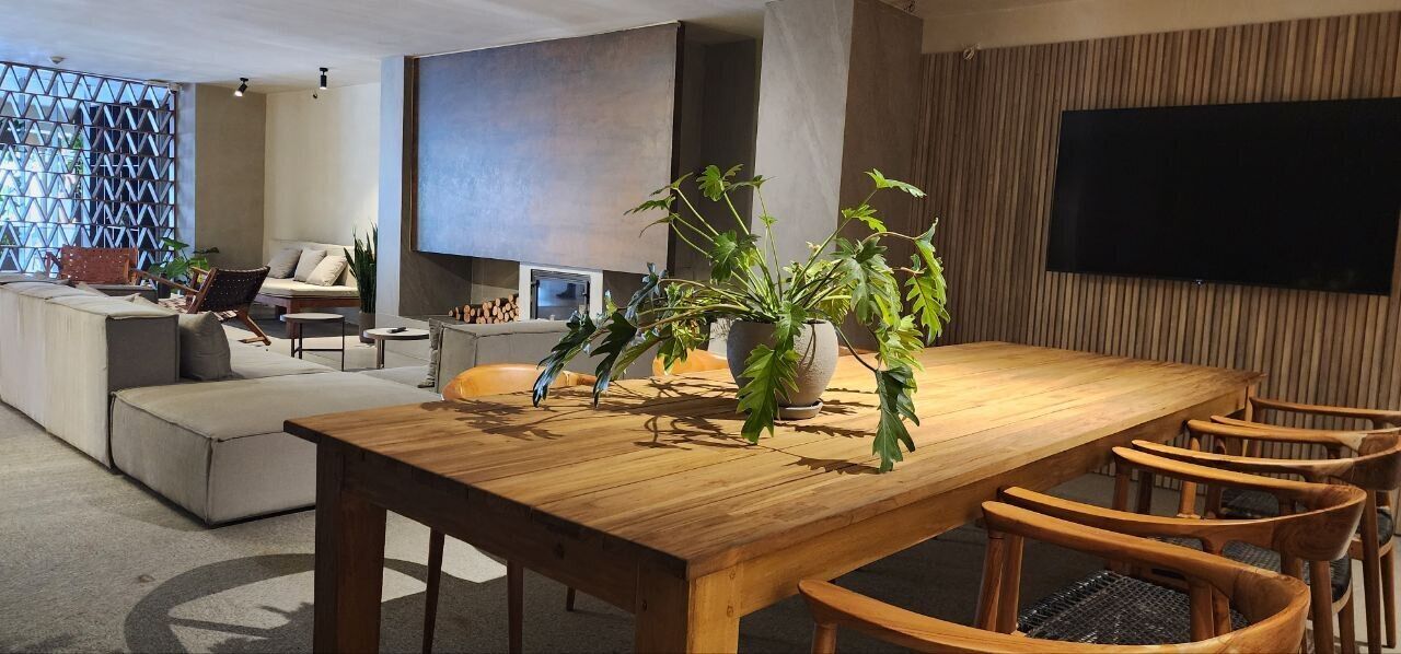 Un salon moderne avec une table à manger en bois, des sièges confortables, un grand téléviseur et une plante décorative.