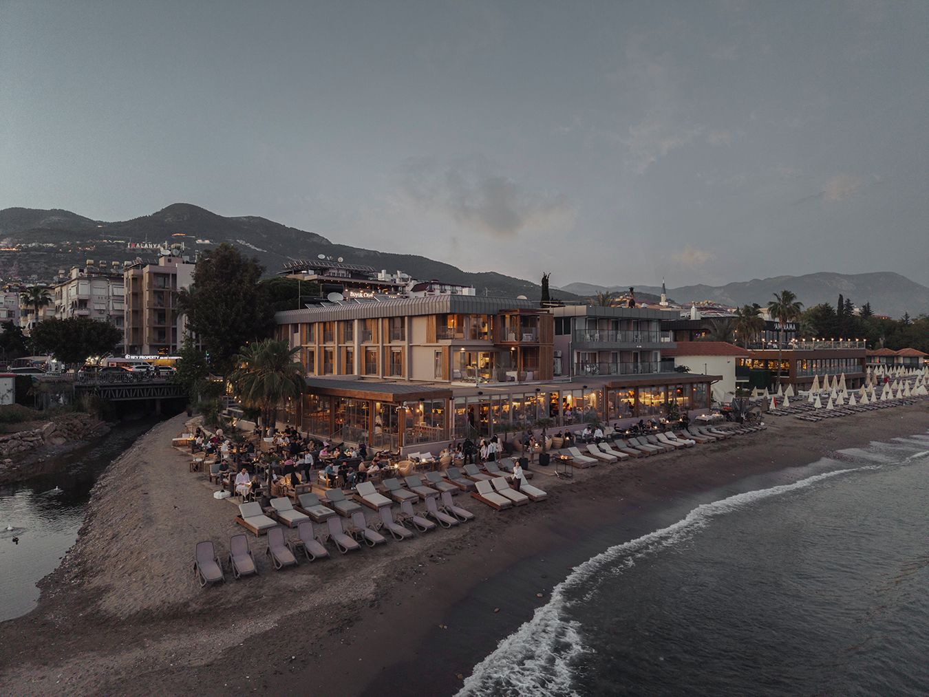 Un hotel costero con varios pisos, zona de estar al aire libre y ubicación frente a la playa.