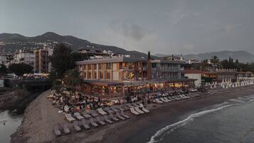 Un hotel costero con varios pisos, zona de estar al aire libre y ubicación frente a la playa.