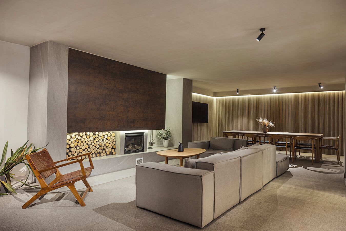 A modern living room with a sectional sofa, a round coffee table, and a fireplace. There is a dining area with a table and chairs.