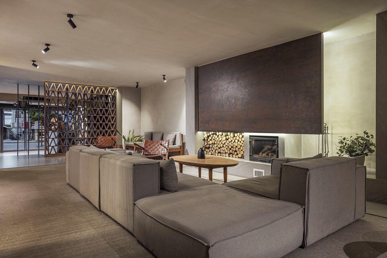 Uma sala de estar moderna com um sofá seccional, uma lareira e um painel decorativo na parede.