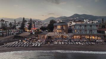 A coastal hotel with outdoor seating and a view of the sea.