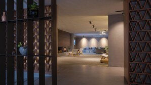 Un interior moderno con suelo de madera, un conjunto de sofás y una pared decorativa con motivos geométricos.